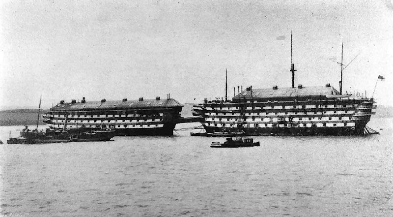 Left is HMS Cambridge, to her right is the Calcutta connected by a bridge. Amazingly HMS Cambridge fired inland over a mudflat using cloth targets on wooden struts stuck in the mud. The gunnery school was moved ashore to HMS Drake in 1907, so this picture obviously predates that.